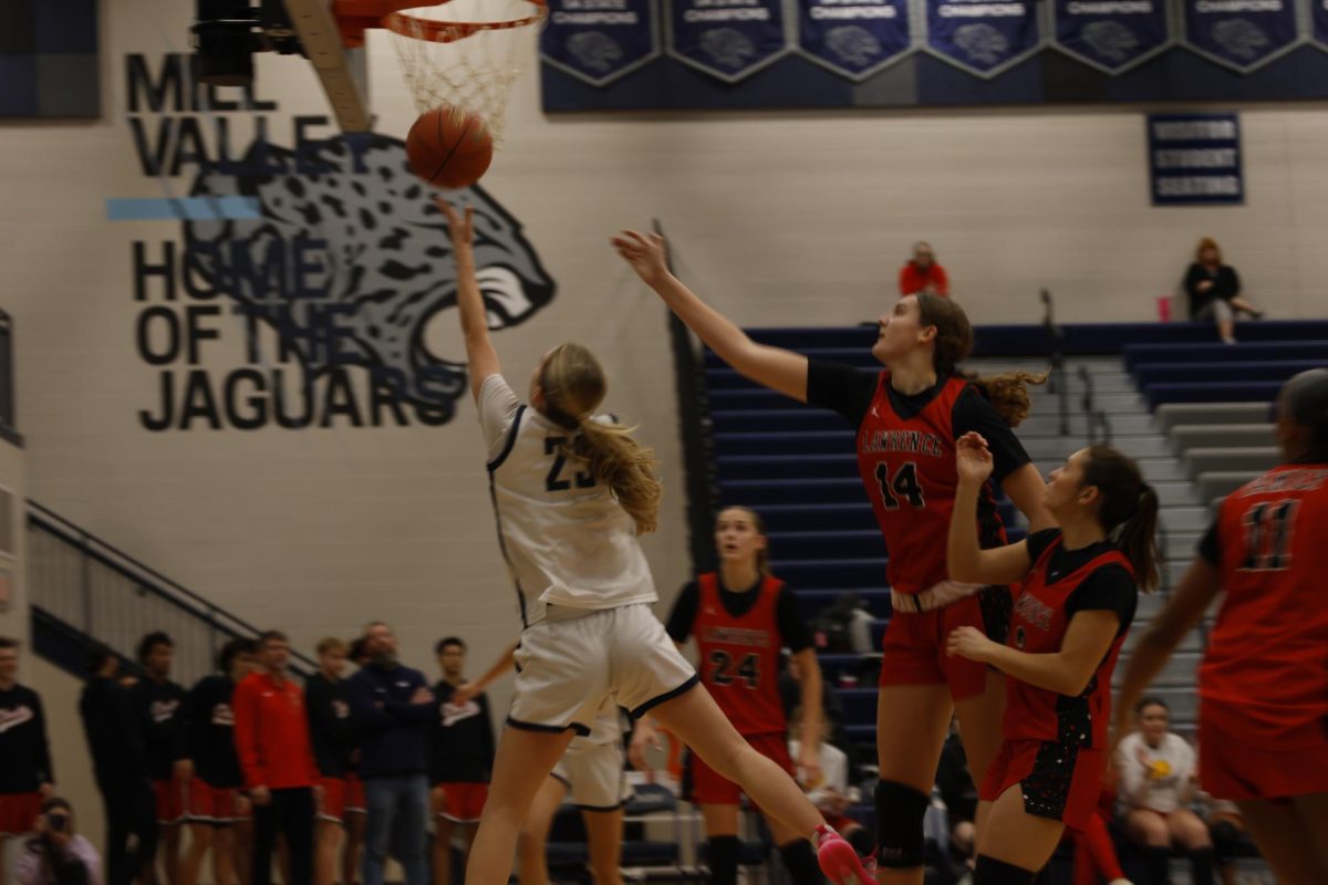 Being swarmed by defenders, junior Riley Marshall pushes the ball up and in