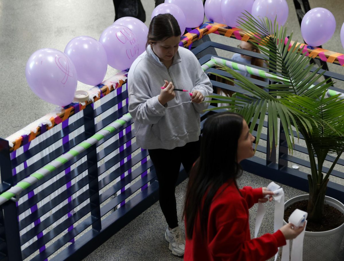 Supplies in hand, sophomore Isabel Leblanc and junior Caitlin Pham help decorate the main stairs. 