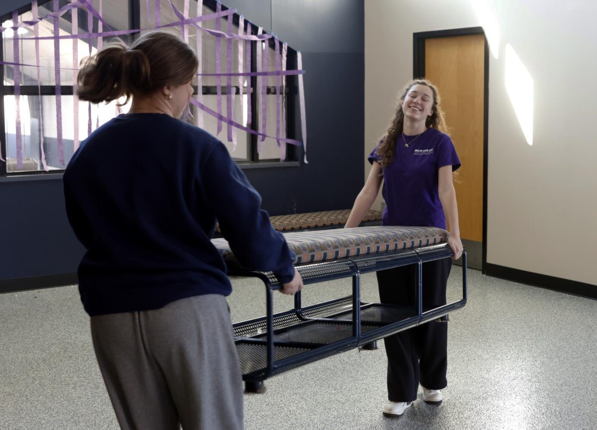 As they move a bench, sophomores Frances Cheshire and Ainsly Leithead laugh together.