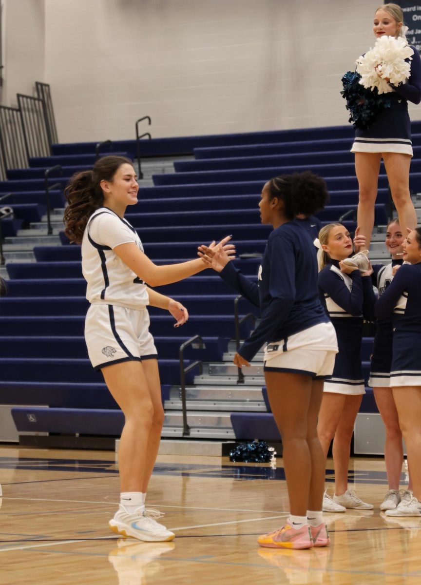 In the starting lineup, senior Paige Roth runs up and does her opening handshake.