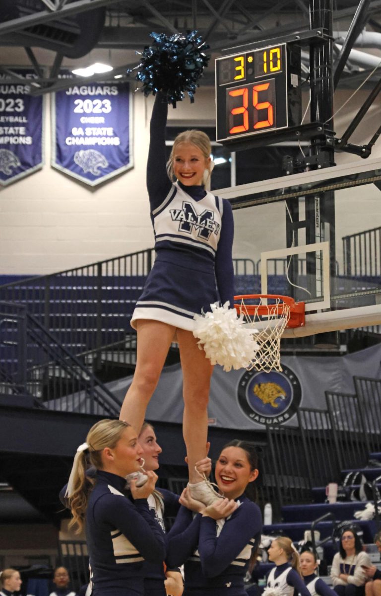 During a timeout, sophomore Lucy Ericson and cheerleaders laugh at their stunt.