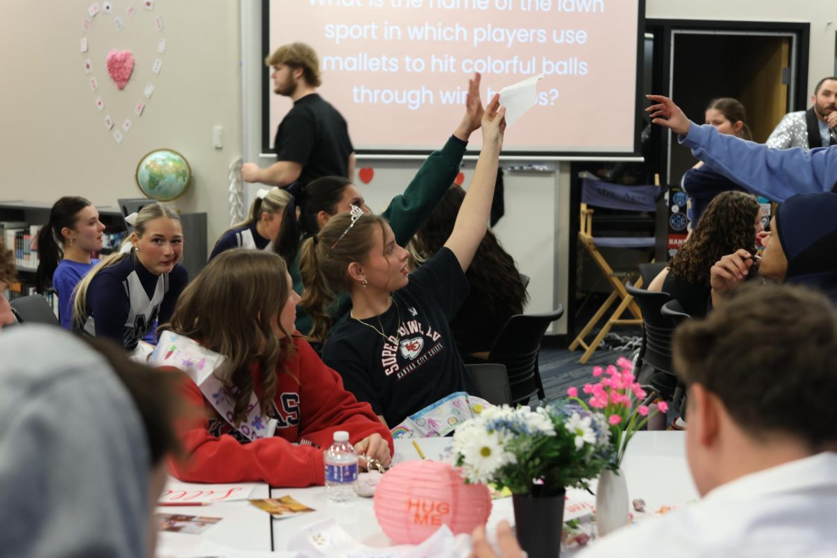 Raising her hand up high, WOCO queen candidate senior Sienna Suderman waits for her team's trivia answers to be picked up. 