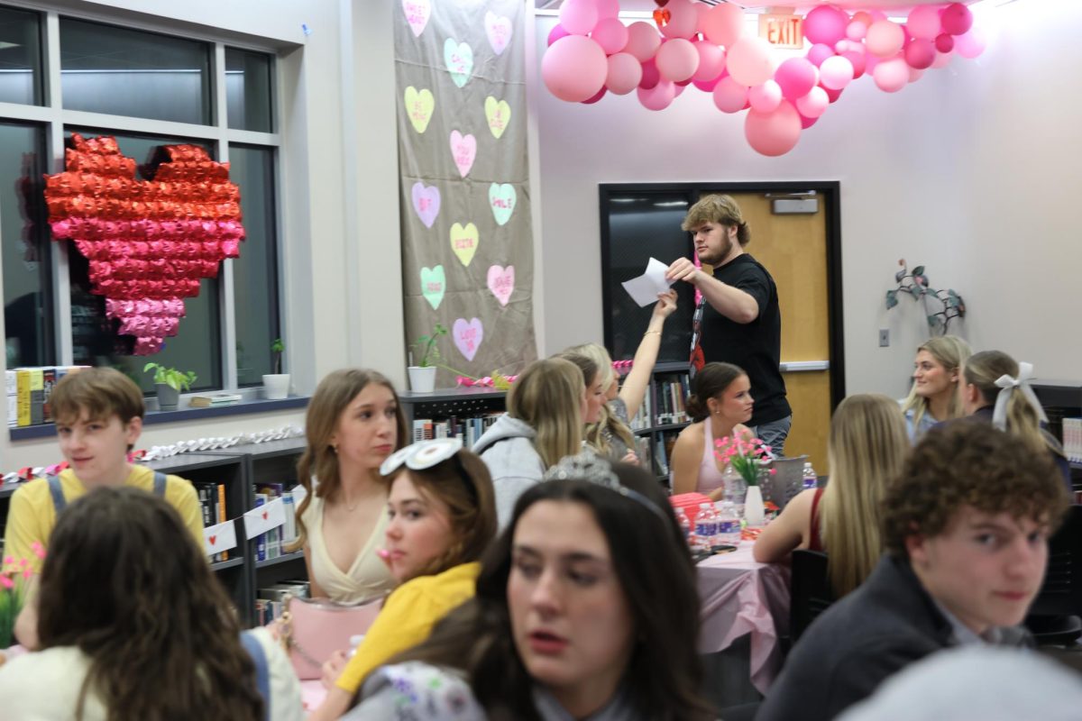 Walking from table to table, sophomore Samuel Thomason walks around to collect trivia answers.