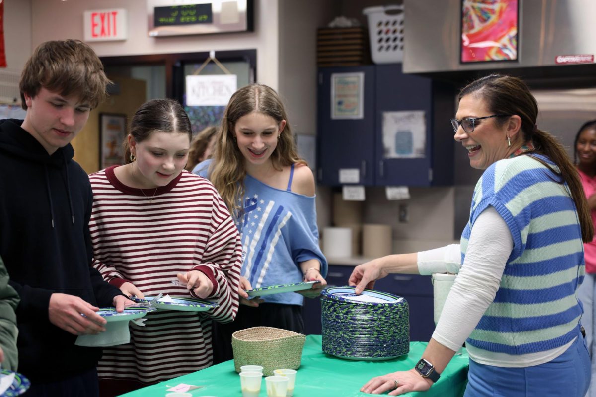 Grabbing a plate, French National Honor Society sponsor Denise Smith talks with students about the fondue party.