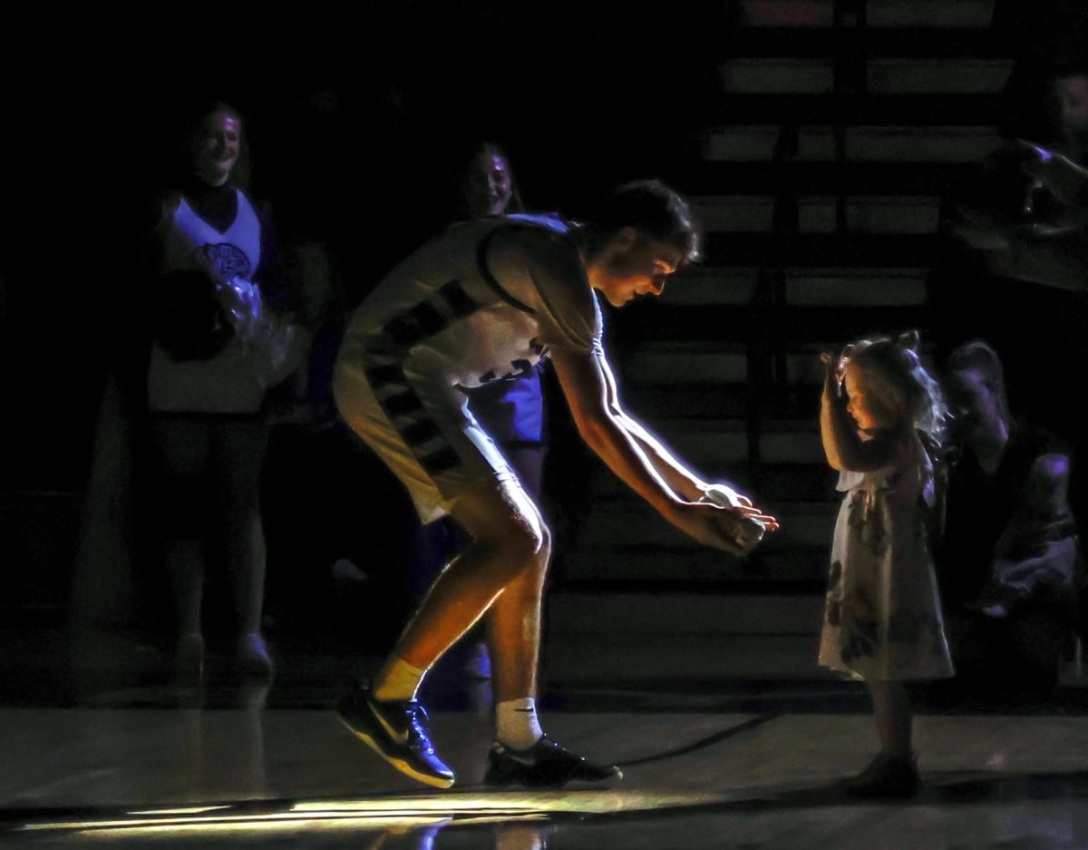 During introductions, senior Carter Clark high-fives coach Marcus Rhodes' daughter who is waiting at the end of the tunnel