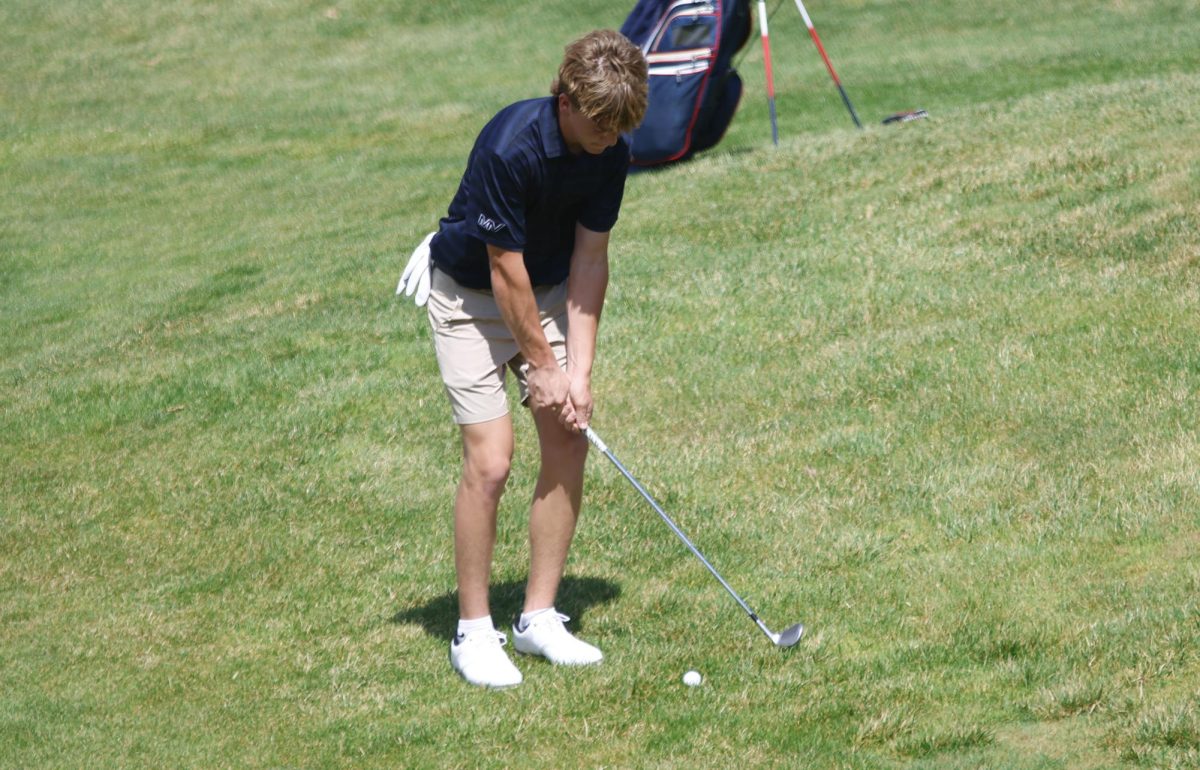 Freshman Liam Dolan swings to hit his ball out of the grass.