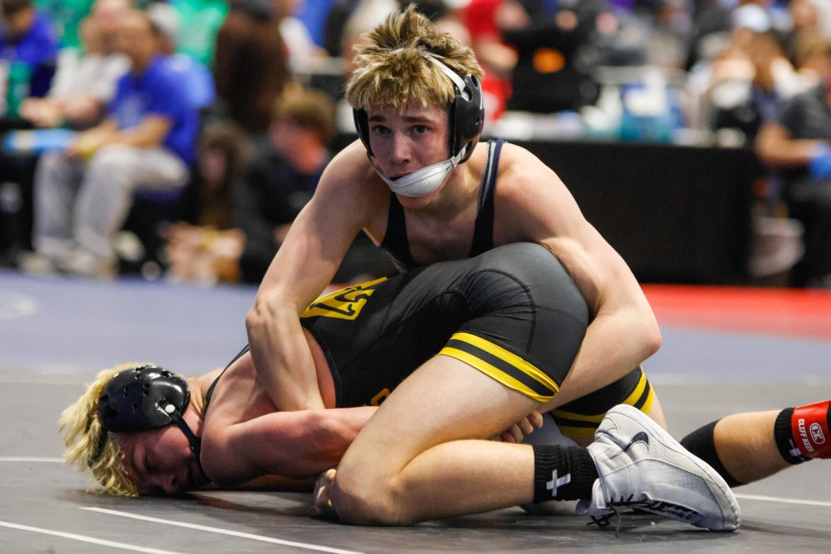 Arms around his opponent, sophomore Liam Grover glances up at his coach for support. 
