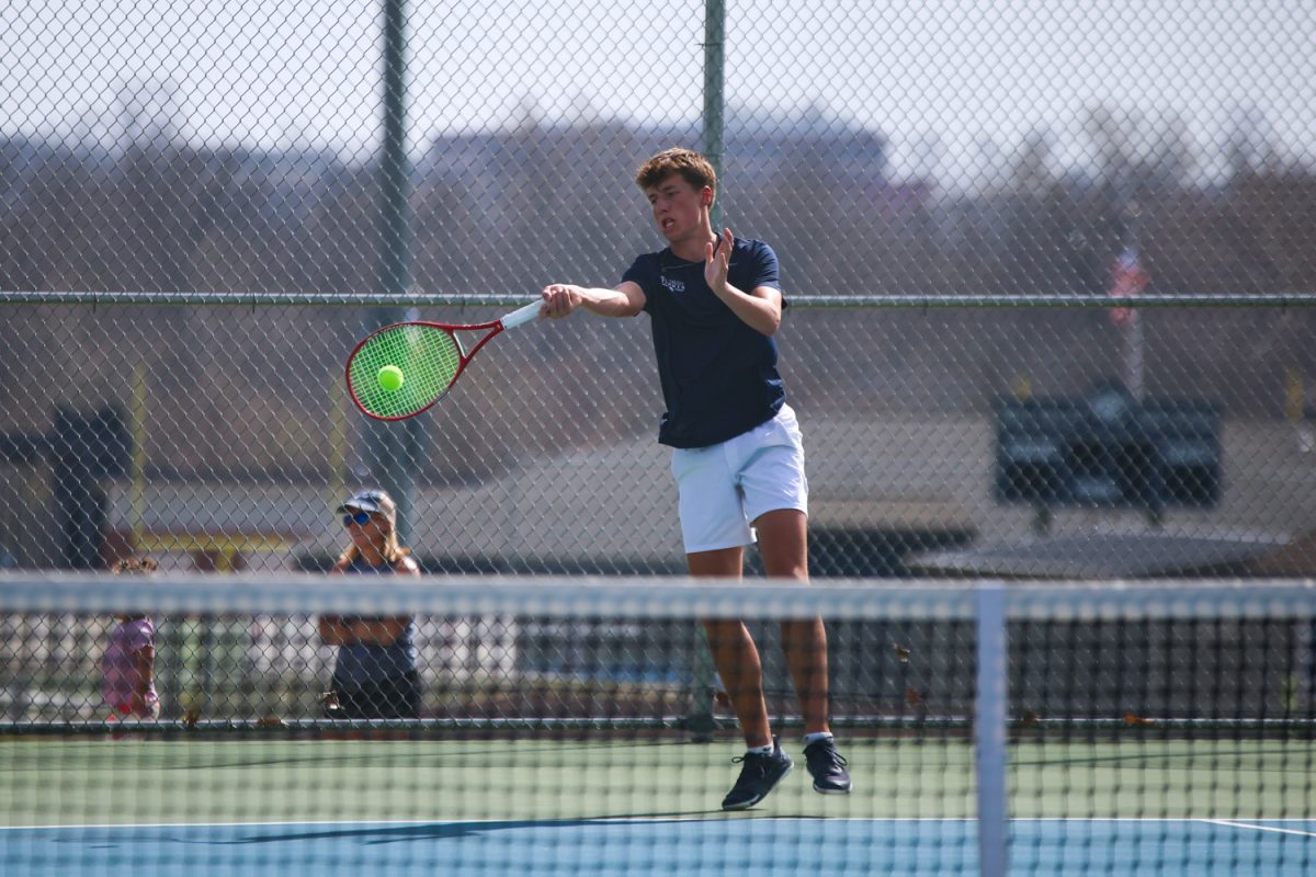 Focusing intently on the tennis ball, junior Jace Hutchens makes contact to hit the ball cross court.