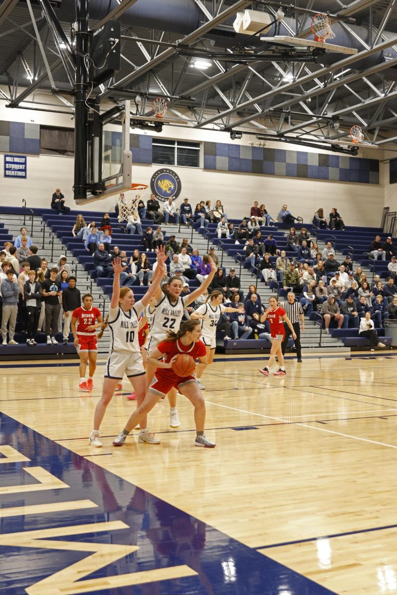 Hands in the air, seniors Leah Konen and Paige Roth block the Shawnee Mission North player.