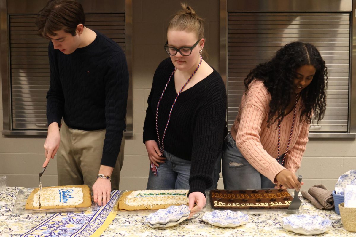 Senior French NHS members Barron Fox, Izzy Simms, and Abby Abebe help cut and serve desserts after the induction ceremony.