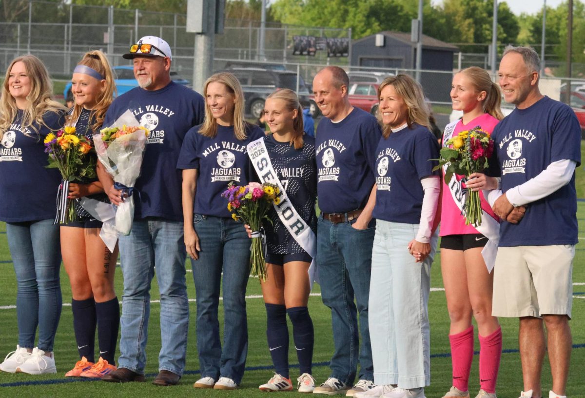 Posing for the photo, all the seniors smile together with their parents.