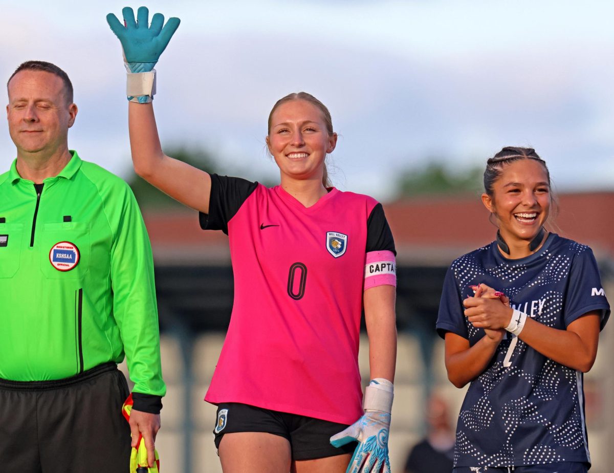 Waving, senior Jamie Ricker smiles in the starting lineup announcement.
