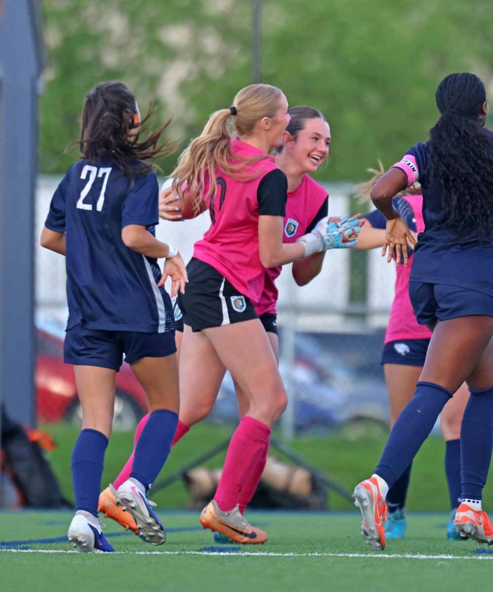 Laughing, senior Jamie Ricker and sophomore Emily Izatt hold each other after their pregame high five.