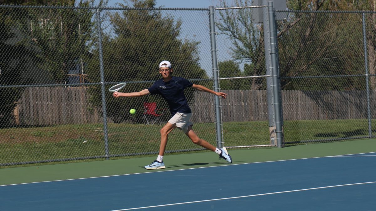 Reaching his racket out, junior Jackson Doll swings at the ball. 