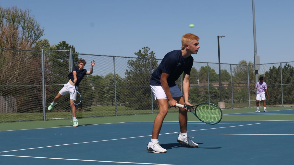 Swinging through, junior Gage Horn serves the ball as his teammate, sophomore Spencer Reed prepares for the ball to come back to him. 