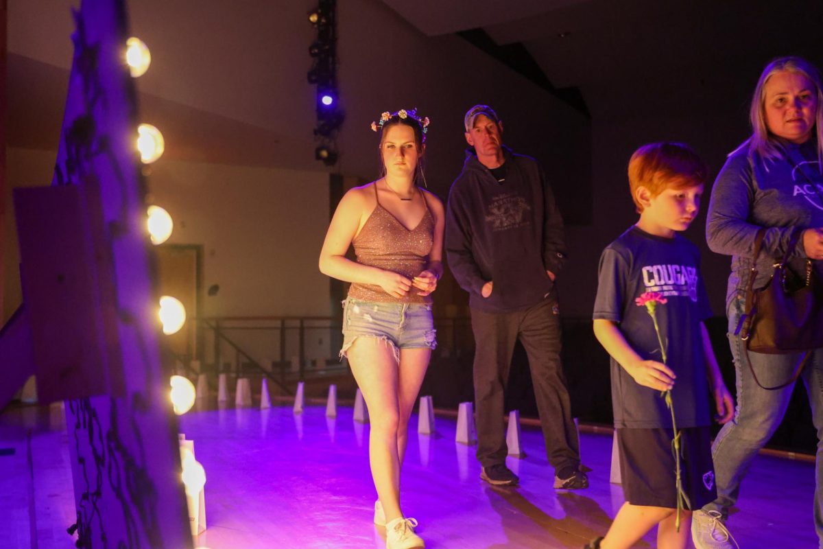 Senior Lydia Barngrover admires the glowing sign as she walks through the luminaria ceremony alongside community members.