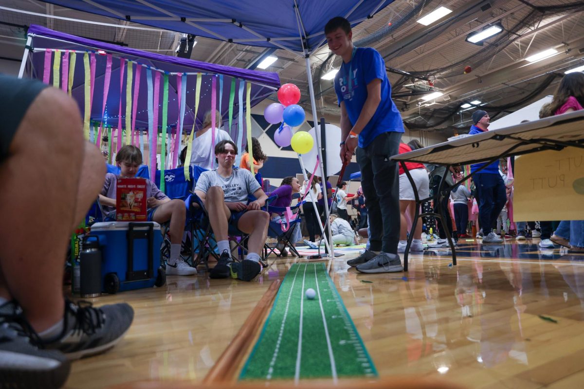 At the putt putt booth Junior Lucas Agre watches his shot go into the hole.