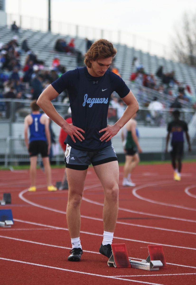 Looking down, junior Hudson Hawkins adjusts his block before his race.