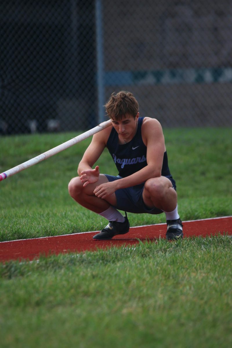 Crouched down, senior Ethan Cooper prepares to vault over the set height.