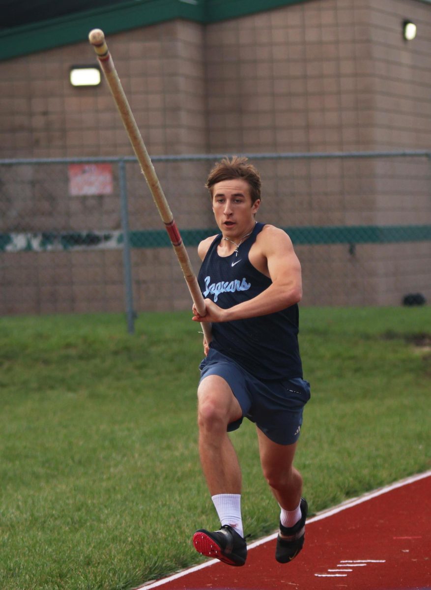Holding the vaulting bar, senior Ethan Cooper approaches the set height.