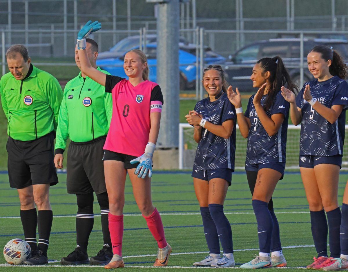 Smiling brightly, senior Jamie Ricker waves to the crowd while being announced for the starting lineup. 