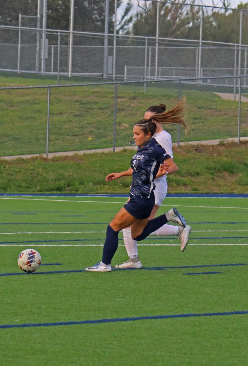 Junior Paige Frost rushes to the ball to get a shot on goal with a defender close behind. 