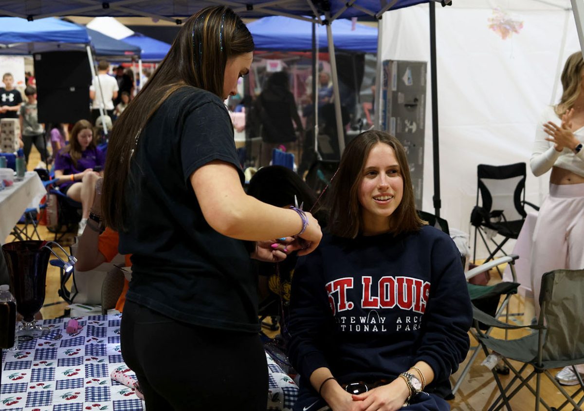 Concentrated on clipping in the hair tinsel, sophomore Grace Hereth adds fake hair to junior Victoria Guess at Relay for Life, Saturday, March 28.