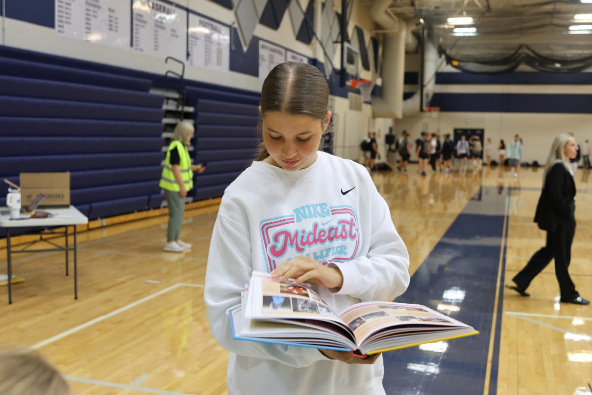 Flipping through the pages, sophomore Ellie Brown smiles as she views the senior ads in her yearbook.