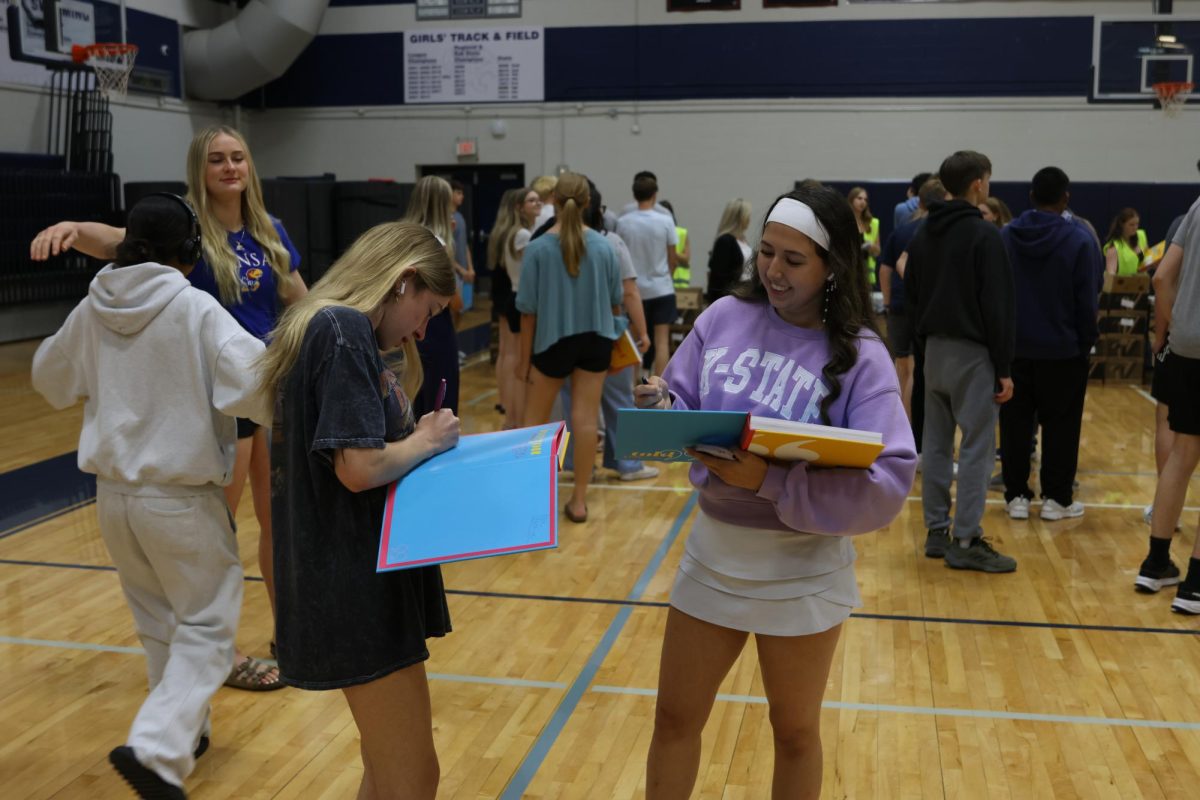 Trading their yearbooks, juniors Lyla Johnson and Lexi Blaine sign the back page while remembering their times together. 