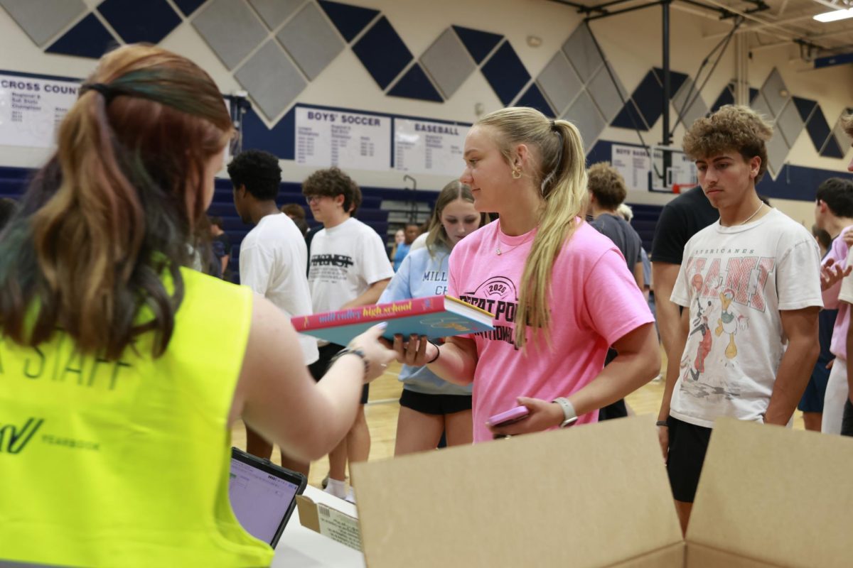Junior Charlie Barret hands Junior Avery Huber her yearbook.