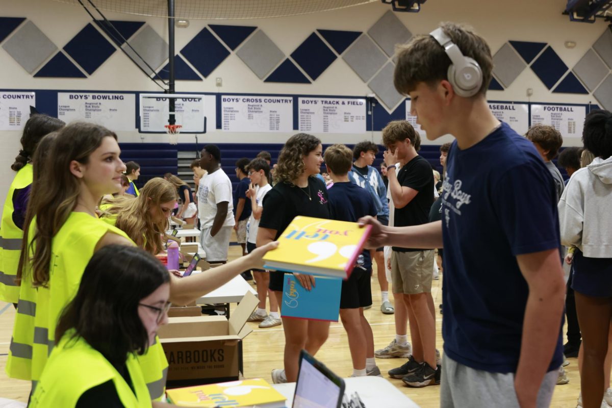 Junior Gracie Policita hands sophomore Cooper Wurm his yearbook.