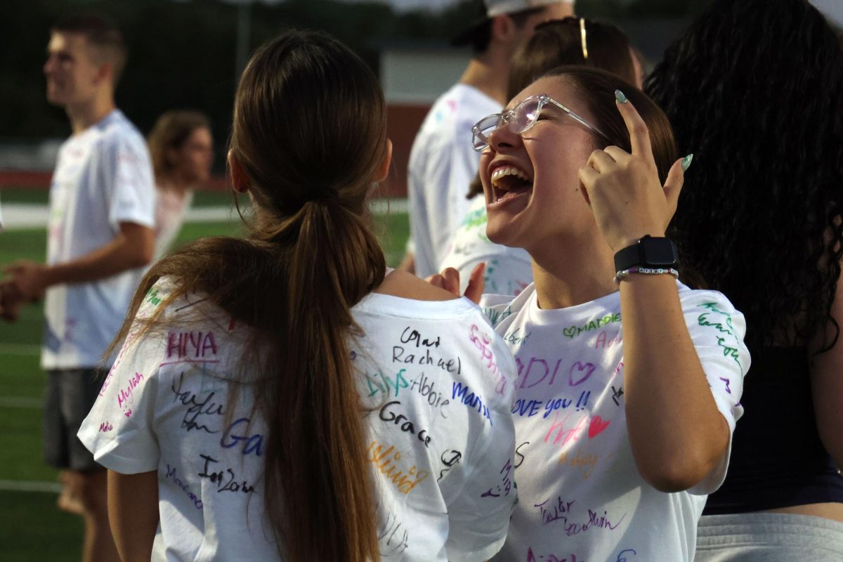 Hand raised, senior Eva Hernandez sings along to the music with senior Stella Harryman.