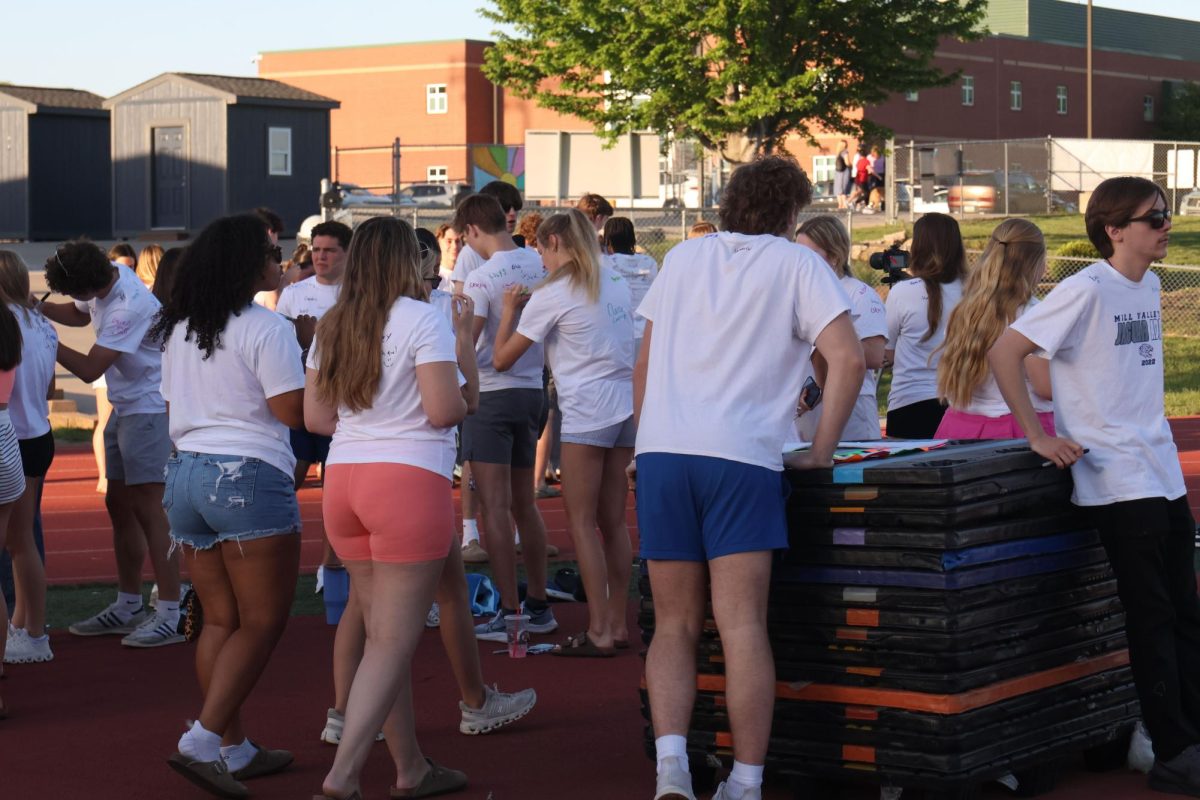 Seniors begin signing each others' white t-shirts after arriving.