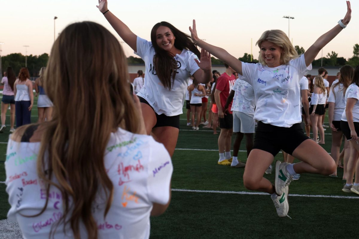 Hands and feet in the air, seniors Abbie Kroupa and Eden Christian jump for a photo.